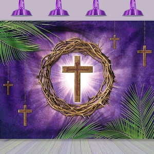 May include: A purple backdrop featuring a wooden cross at the center, encircled by a crown of thorns. Additional wooden crosses hang from chains, with palm fronds and a bright light emanating from behind the central cross. Decorative purple lights are at the top.