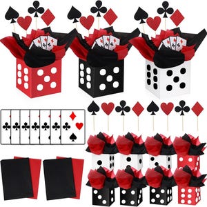 May include: A casino-themed party decoration set featuring three large dice-shaped boxes in red, black, and white, filled with red and black tissue paper, playing card cutouts, and suit symbols on sticks, plus additional small dice boxes and card sets.