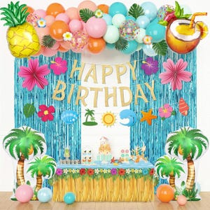 Puede incluir: Decoración de fiesta de cumpleaños con temática tropical. La escena incluye un arco de globos con globos con forma de piña y coco, una pancarta dorada de "Happy Birthday" y decoraciones de palmeras. La mesa está decorada con una falda de hierba.