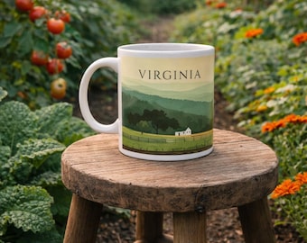 May include: A white ceramic mug with the word "VIRGINIA" printed on it, featuring a landscape design of rolling green hills, trees, and a small white house. The mug sits on a small, round wooden stool in a garden setting.