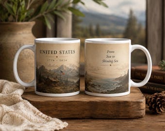 May include: Two white ceramic mugs with a vintage design. One mug features the text "UNITED STATES 1776 - 2026" with a landscape illustration. The other mug has the text "From Sea to Shining Sea" with a coastal scene.