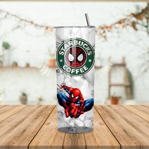 May include: A stainless steel tumbler with a marble effect design, featuring the Starbucks Coffee logo with a Spider-Man graphic. The tumbler has a silver straw and is on a wooden table.