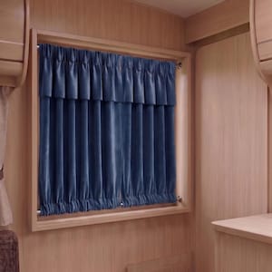 May include: A blue velvet curtain hangs in a wooden framed window. The curtain is gathered at the top and bottom, with a valance above. The interior of the room is paneled with light wood.