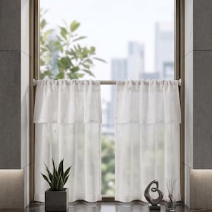 Könnte beinhalten: Weiße, transparente Gardinen mit Rüschen oben, vor einem Fenster aufgehängt. Eine Topfpflanze und dekorative Objekte stehen auf der Fensterbank. Der Fensterrahmen ist goldfarben.
