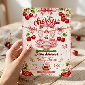 May include: A cream-colored baby shower invitation card featuring red cherries, pink gingham patterns, and a central illustration of a ruffled baby outfit on a hanger. Text includes 'She is the cherry on top', 'Baby Shower', 'Emily Brown', and event details.