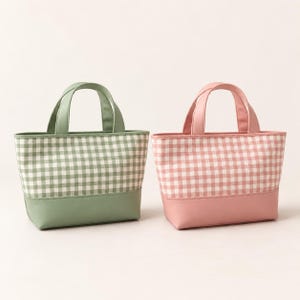 May include: Two small tote bags with top handles. One bag features a sage green and white gingham pattern on the upper portion with a solid sage green base. The other bag features a dusty pink and white gingham pattern with a solid dusty pink base.