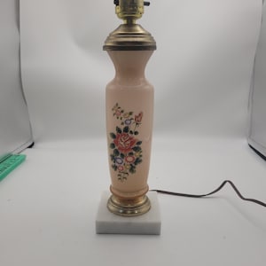 Collectible antique Bristol glass boudoir lamp featuring a pink opaline glass body with a hand-painted floral design, a brass socket, and a