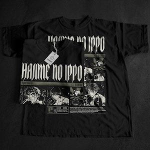 May include: Black t-shirts featuring anime-style illustrations and text. The front shirt displays "Hajime no Ippo" in a gothic font, with character art and the text "Fight Hard." A second shirt is visible in the background.