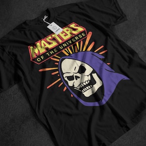 May include: Black t-shirt featuring the "Masters of the Universe" logo in yellow and red, with a graphic of Skeletor's skull in a purple hood. The shirt has a "Large" tag.