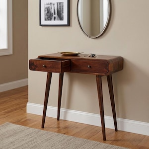 May include: A dark brown wooden console table with four tapered legs and two drawers. The left drawer is pulled open, revealing the interior. A small gold-toned dish and a set of metal keys rest on the flat top surface of the table.