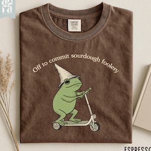 May include: A white ceramic mug with a black handle and the text "But First, Coffee" in a black, handwritten-style font. The mug is on a white surface.