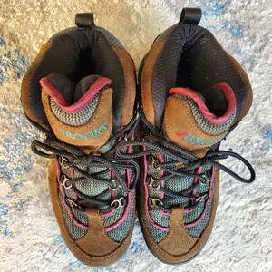 Peut inclure: Une paire de chaussures de randonn&eacute;e brunes avec des accents turquoise et roses. Les chaussures ont des lacets noirs et le mot "Brooks" est &eacute;crit sur le c&ocirc;t&eacute;.