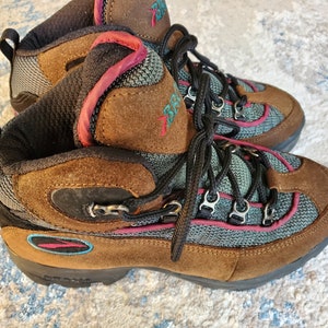 Peut inclure: Bottes de randonn&eacute;e marron avec des accents turquoise et rose. Les bottes ont une fermeture &agrave; lacets et une semelle ext&eacute;rieure robuste.