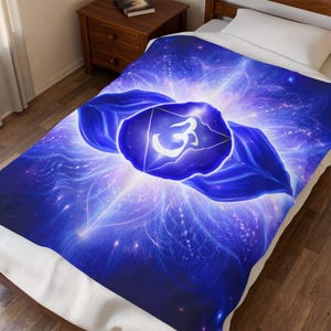 May include: A blue and white blanket with a spiritual design. The blanket features a central blue shape with a white symbol, surrounded by a radiating pattern of blue and white light. The blanket is on a bed.