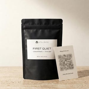Pode incluir: Uma embalagem preta de matcha cerimonial "FIRST QUIET" de Kyoto, Jap&atilde;o, com um r&oacute;tulo branco e o logotipo "STILLRISE". Um pequeno cart&atilde;o com um c&oacute;digo QR e o texto "Ritual Kit Access" est&aacute; ao lado da embalagem. O peso l&iacute;quido &eacute; de 30g.