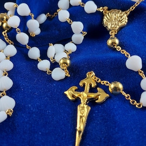 Peut inclure: Chapelet de prière blanc avec une croix dorée et un centre doré. Les perles sont en plastique blanc et la croix est en métal.