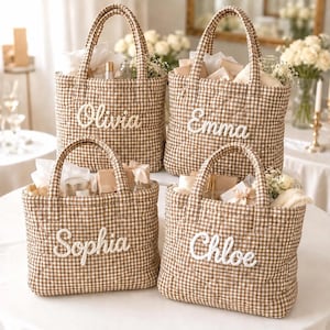 May include: Four quilted tote bags in a brown and white gingham pattern, each featuring a white embroidered name on the front. The names displayed are Olivia, Emma, Sophia, and Chloe. Each bag is filled with various items and white floral accents.