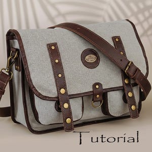 May include: A gray messenger bag with brown leather trim and straps. The bag features a flap closure, two front pockets, and brass-colored rivets. The text "Tutorial" is visible at the bottom of the image. The bag has a shoulder strap and a top handle.