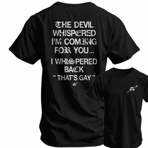 May include: Black t-shirt with white text: "THE DEVIL WHISPERED I'M COMING FOR YOU... I WHISPERED BACK 'THAT'S GAY'". A smaller version of the shirt is visible on the right, featuring a skull and trident graphic.