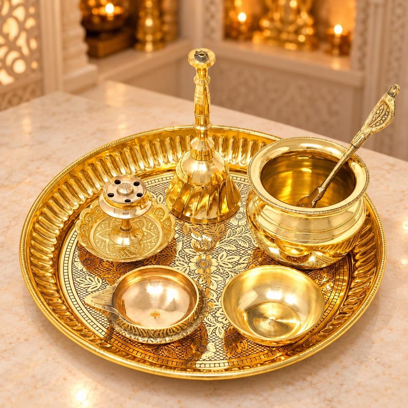 May include: A polished brass set featuring a large round tray with an intricate floral pattern, a tall bell, a small incense burner, a deep bowl with a long-handled spoon, and two small open dishes, all arranged together on a flat surface.