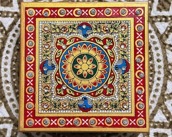 May include: A square decorative box featuring a central floral mandala design in yellow, red, and green. The border is painted red with white cross patterns and embedded clear rhinestones. Blue bird motifs are positioned around the center.