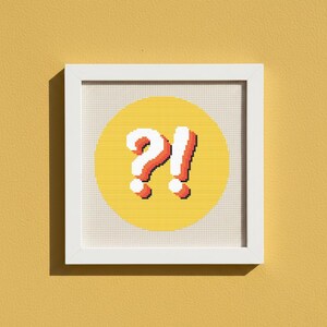 Puede incluir: Una obra de arte en punto de cruz enmarcada que presenta un círculo amarillo con un signo de interrogación y un signo de exclamación blancos en rojo con un contorno blanco. La obra está sobre un fondo amarillo.