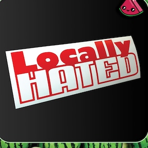 Peut inclure: Un autocollant blanc avec les mots "Locally Hated" en lettres rouges gras. L'autocollant est rectangulaire et posé sur un fond noir avec une bordure sur le thème de la pastèque.