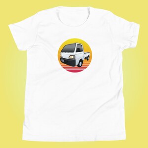 Peut inclure: Camionnette blanche avec un graphique de coucher de soleil rouge, orange et jaune derrière elle. Le camion est dans un cercle.