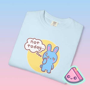 Close up folded pastel blue graphic tee showing blue bunny illustration and “not today” phrase, funny antisocial mood shirt