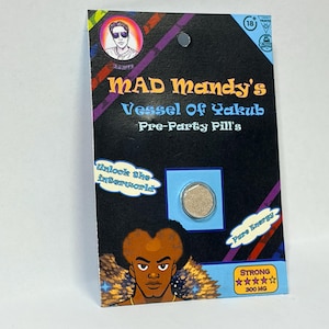 Op de afbeelding: Een zwart en kleurrijk productpakket met de tekst "MAD Mandy's Vessel Of Yakub Pre-Party Pill's". Het pakket bevat een cartoonillustratie en een kleine, ronde pil. De tekst "Unlock the interworld" is ook zichtbaar.