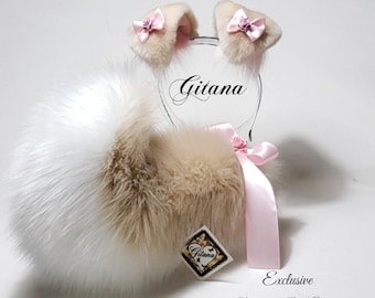 May include: A set of beige and white faux fur animal ears on a headband, featuring small pink satin bows with tiny roses. A fluffy faux fur tail in matching beige and white is attached with a pink satin ribbon. The text Gitana is visible.