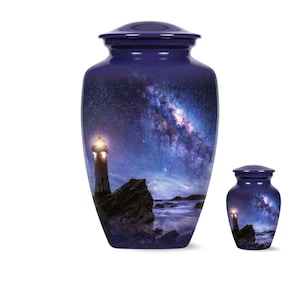Puede incluir: Dos urnas funerarias de color azul oscuro de diferentes tamaños, cada una con un cuerpo cilíndrico y una tapa a juego. La superficie muestra una escena nocturna con un faro brillante en una costa rocosa bajo un cielo estrellado violeta y azul.