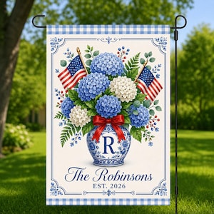 May include: A garden flag featuring a blue and white floral arrangement in a vase, with two American flags. The vase has the letter "R" and a red bow. The flag reads "The Robinsons EST. 2026" and has a blue gingham border.