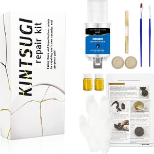 May include: Kintsugi repair kit with a white box, gold accents, and the text "Kintsugi repair kit." Includes a tube, two small bottles, brushes, and instructions. The kit is designed for repairing ceramics.