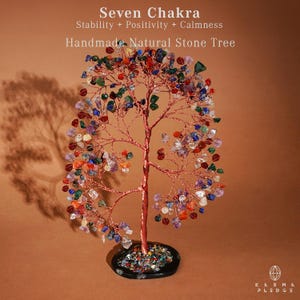May include: A handmade natural stone tree sculpture with a copper wire trunk and branches. The tree is adorned with colorful gemstones, including red, blue, green, and purple stones. The base is a black, circular dish filled with small stones. Text on the image reads "Seven Chakra".