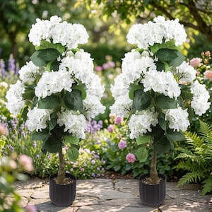 May include: Two artificial hydrangea topiary trees featuring clusters of white flowers and green leaves. Each tree is planted in a dark gray, vertically ribbed cylindrical pot, standing upright with a visible brown textured trunk.