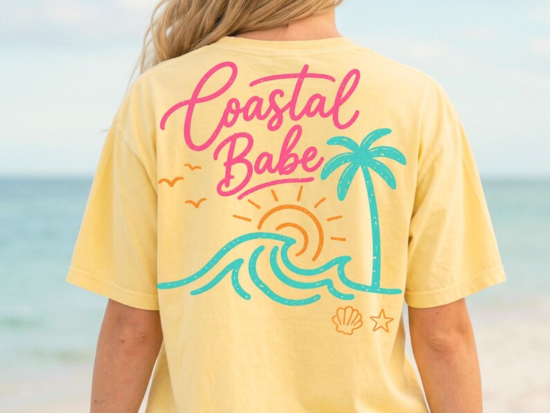 May include: Yellow t-shirt with a beach-themed graphic on the back. The design includes the words "Coastal Babe" in pink and a turquoise palm tree, waves, and sun. A seashell and star are also included.