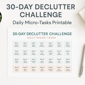 May include: A printable 30-Day Declutter Challenge with daily micro-tasks. The white paper has a grid of tasks, a succulent in a white pot, a pen, and a stack of white notepads. The text reads "30-DAY DECLUTTER CHALLENGE" and "Daily Micro-Tasks Printable."