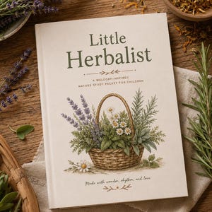 Peut inclure: Un livre intitulé "Little Herbalist" avec une illustration d'un panier d'herbes et de fleurs sur la couverture. Le livre est sur une surface en bois avec de la lavande et du romarin. Le texte indique "A Waldorf-Inspired Nature Study Packet for Children".