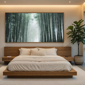 Puede incluir: Una cama de plataforma de madera de perfil bajo con cabecero a juego y mesitas de noche integradas, cubierta con un edredón y almohadas blancas. Sobre la cama cuelga un gran cuadro horizontal enmarcado de un bosque de bambú brumoso.