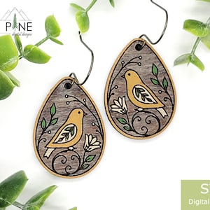 May include: Teardrop-shaped wooden earrings featuring a yellow bird perched on a black scrollwork branch with white flowers and green leaves. The design includes dark metal hooks. The image displays the text LONE PINE digital designs and SVG Digital File Only.
