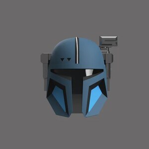 Puede incluir: Un casco azul y gris con un dise&ntilde;o distintivo, con una franja vertical central y detalles angulares. El casco tiene una visera y un accesorio rectangular en el lateral, sobre un fondo gris.
