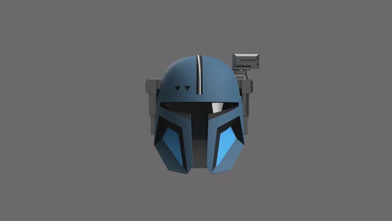 Puede incluir: Un casco azul y gris con un dise&ntilde;o distintivo, con una franja vertical central y detalles angulares. El casco tiene una visera y un accesorio rectangular en el lateral, sobre un fondo gris.