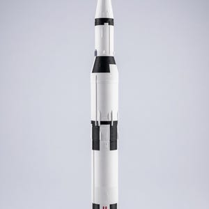 May include: A white ceramic mug with a black handle and the text "But First, Coffee" in a bold, black font. The mug is set against a blurred background, suggesting a cozy setting.