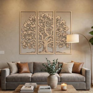 Puede incluir: Arte mural de madera de tres paneles con un diseño detallado de árbol. La obra de arte es de color marrón claro y está colocada contra una pared de tono neutro. La habitación también incluye un sofá gris con cojines marrones y beige, una mesa de centro de madera y una lámpara de pie.