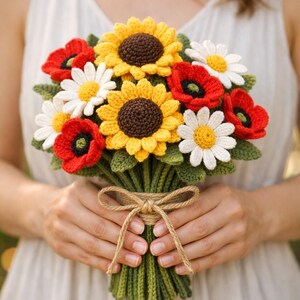 May include: A handmade crochet bouquet featuring sunflowers, daisies, and poppies. The flowers are yellow, white, and red with green leaves and stems. The bouquet is tied with twine.