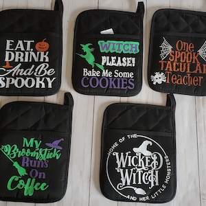 Peut inclure: Ensemble de six maniques matelass&eacute;es noires avec des broderies sur le th&egrave;me d'Halloween. Les motifs comprennent "Eat, Drink and Be Spooky", "Witch Please! Bake Me Some Cookies", "One Spooktacular Teacher", "My Broomstick Runs On Coffee", "Home of the Wicked Witch and Her Little Monsters", et une sorci&egrave;re avec un chaudron.