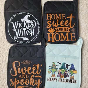 Peut inclure: Quatre maniques de four sur le th&egrave;me d'Halloween. Deux maniques noires avec du texte orange, l'une avec "Home of the Wicked Witch and her little monsters" et l'autre avec "Home sweet haunted home". Une manique bleue avec un message "Happy Halloween" et trois gnomes. Une manique noire avec du texte orange qui dit "Sweet and spooky".
