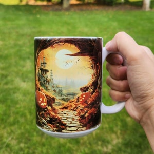 May include: A white ceramic mug with a Halloween-themed design. The design features a path leading through a forest with a full moon in the sky. There are pumpkins and a castle in the background.