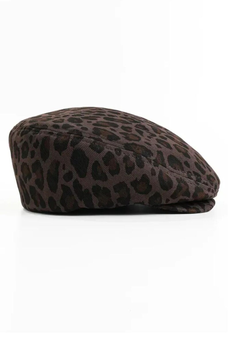 May include: A brown flat cap with a leopard print pattern. The cap is made of a textured fabric and features a classic design. This hat is a stylish accessory for various outfits.
